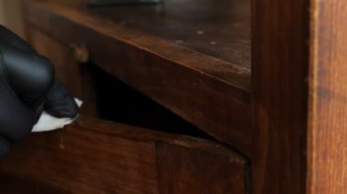 Paçavralı bir tamirci mobilyaların pisliklerini yıkar. Eski ahşap yüzeyin restorasyonu.