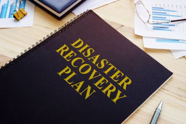 Disaster recovery plan book and stack of papers. clipart