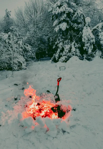 bonfire in the forest in winter near a shovel