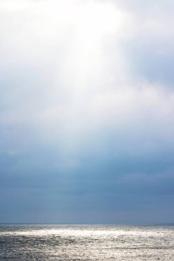 Bulutların arasından geçen ışık ışınları, cennetten yeryüzüne denizde bir nokta parlıyor.