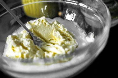 Yumuşak tereyağlı ve şekerli bardakta, çatalla karıştırılmış. Kurabiye, pasta ve kek için hamur hazırlığı. Siyah bir masa ve bir kavanoz şeker..