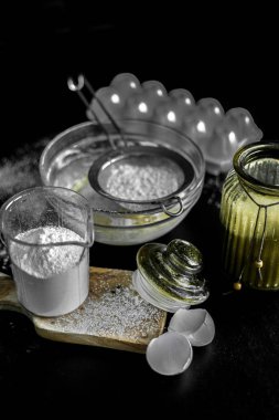 Ev yapımı için malzemeler: kurabiye, ekmek, pasta. Un, şeker ve yumurtalar siyah masada. Fırın yemekleri..