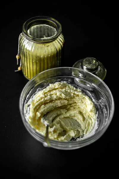 Yumuşak tereyağlı ve şekerli bardakta, çatalla karıştırılmış. Kurabiye, pasta ve kek için hamur hazırlığı. Siyah bir masa ve bir kavanoz şeker..