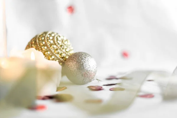New year and Christmas card, colorful gold and silver baubles with ribbon, candles and confetti on a white background. selective focus. top view