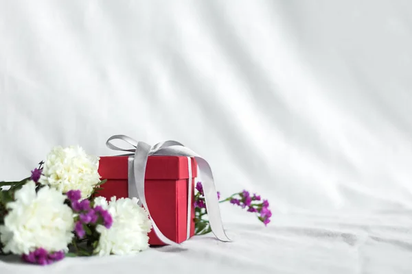 Ramo de flores y caja de regalo cumpleaños, feliz día de la madre y el día de San Valentín sobre un fondo textil blanco. Tarjeta de regalo. Enfoque selectivo. espacio de copia —  Fotos de Stock