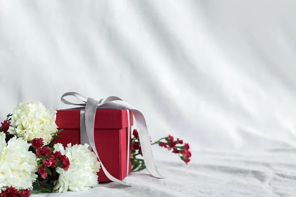 Ramo de flores y caja de regalo cumpleaños, feliz día de la madre y el día de San Valentín sobre un fondo textil blanco. Tarjeta de regalo. Enfoque selectivo. espacio de copia —  Fotos de Stock