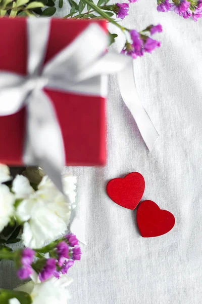 gift box, flowers and hearts.Concept of love, birthday, Happy mother's Day and Valentine's day on a white fabric background. Gift card. Selective focus.