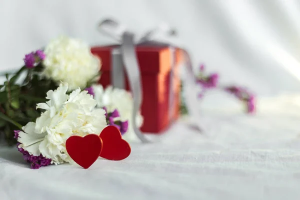 gift box, flowers and hearts.Concept of love, birthday, Happy mother's Day and Valentine's day on a white fabric background. Gift card. Selective focus. Space for text