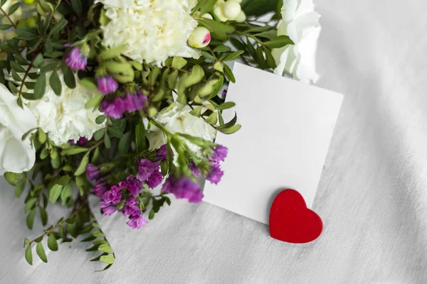 Postal con flores, corazón y una etiqueta vacía para el texto. Saludo romántico y sorpresa. Concepto de amor, Feliz Día de la Madre y Día de San Valentín sobre fondo blanco. Enfoque selectivo. espacio de copia —  Fotos de Stock