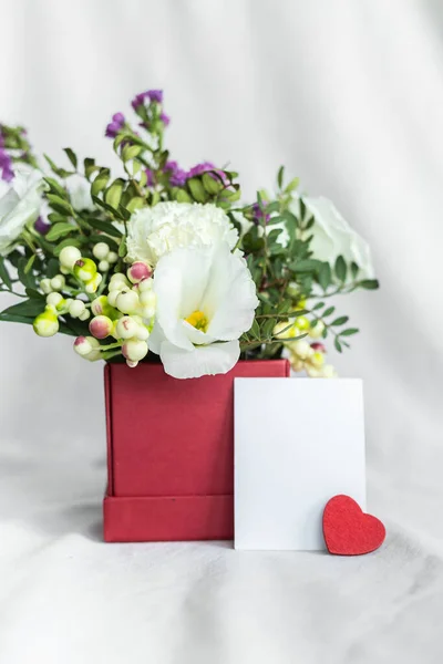 Postcard with a flowers and an empty tag for text. Romantic greeting and surprise. Concept of love, birthday, Happy mother's Day and Valentine's Day on white background. Selective focus. copy space