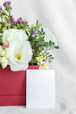 Postcard with a flowers and an empty tag for text. Romantic greeting and surprise. Concept of love, birthday, Happy mother's Day and Valentine's Day on white background. Selective focus. copy space