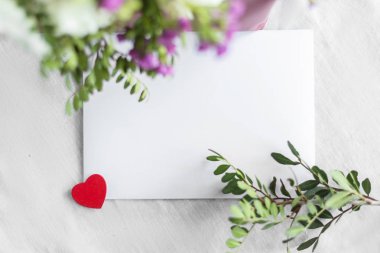 Beyaz bir arka planda mektup ve çiçekler. Düğün davetiyesi ya da aşk mektubu. Aşk konsepti, Anneler Günün ve Sevgililer Günün kutlu olsun. Yukarıdan görünüm. Boşluğu kopyala