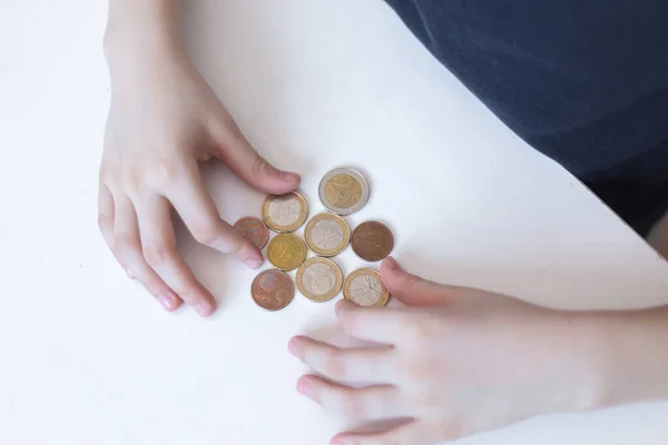 Bozuk para kuleleri inşa ediyorum. Kazakistan tenge sikkesini tutan bir çocuğun el resmi ve bir yığın madeni paraya ekleniyor.