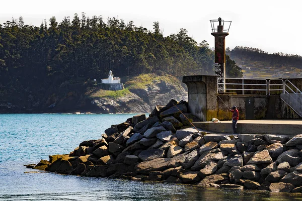 Fishing near a lighthouse in a harbor — Stock Photo, Image