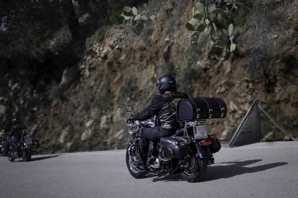 Motosikletli bir motosikletli, köy yolunda gidiyor.