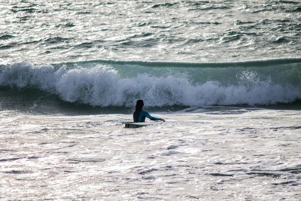 Suda dalgayı bekleyen bir kızın silueti.