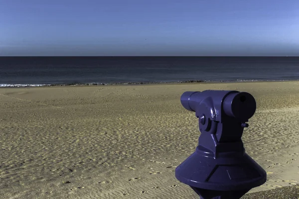 Arka planda kumsal olan mavi teleskop.