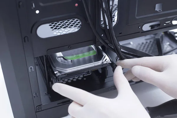 Bilgisayar donanımı parçaları birleştiren bir teknisyenin elleri. Sabit disk yeni bir bilgisayara yükleniyor