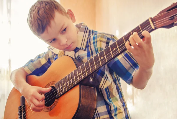 Pojken att lära sig spela akustisk gitarr. I en blå skjorta. — Stockfoto