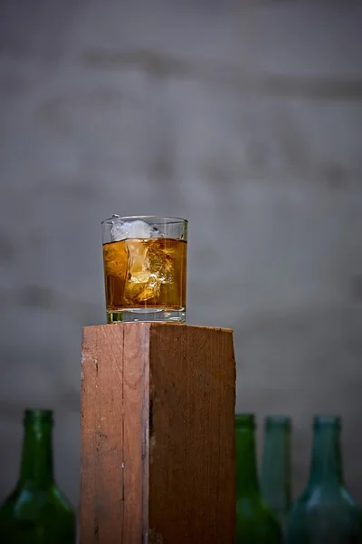 Glass of whiskey with ice on old wooden bar — Stock Photo, Image