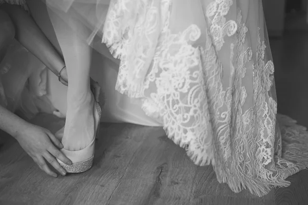 Damigella d'onore aiutare la sposa a indossare scarpe eleganti. Colpo in bianco e nero — Foto Stock