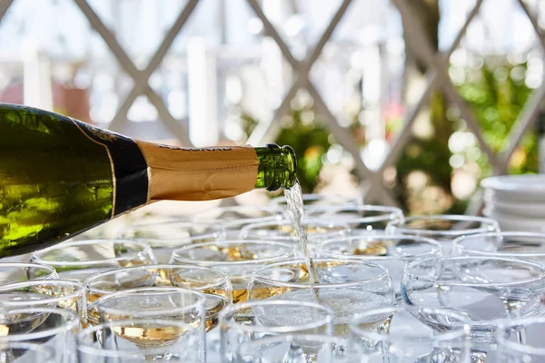 Pouring champagne in flutes standing on table — Stock Photo, Image