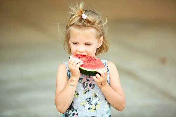 Adorable chica rubia come una rebanada de sandía al aire libre . — Foto de Stock