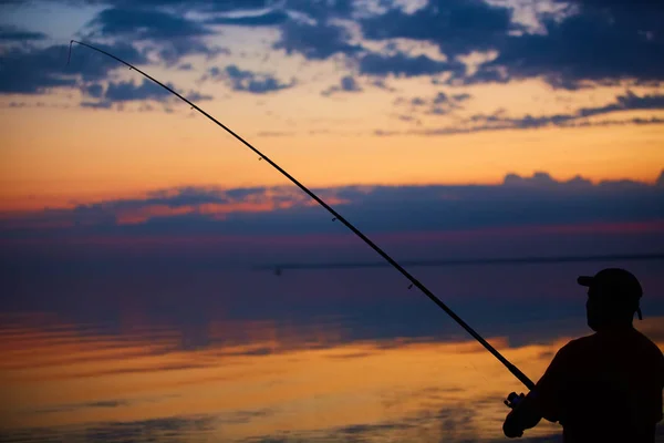 Silhouette de pêcheurs sur un océan calme avec des rayons coucher de soleil — Photo