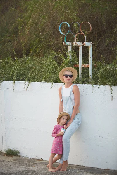 Hipster mom in straw hat with daughter barefoot. Film style