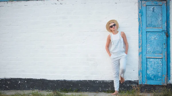 Jolie femme élégante blonde bronzée mince en chapeau de paille et lunettes de soleil posant — Photo