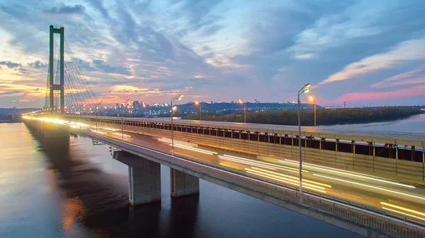 Puente de automóvil y ferrocarril en Kiev, la capital de Ucrania. Puente al atardecer sobre el río Dniéper. Puente de Kiev sobre el telón de fondo de una hermosa puesta de sol en Kiev. Puente en el sol de la noche — Foto de Stock