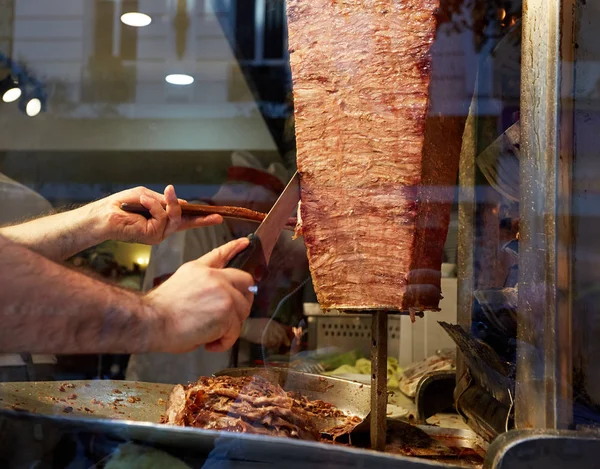 An arm moving to cut the kebab meat — Stock Photo, Image