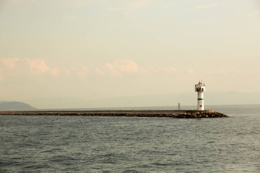 Güzel deniz feneri ile. Sakin deniz ve iskelede bir deniz feneri. Sonsuz deniz küçük ulusumuza yol gösteriyor. Manzara ve işarete. Deniz feneri