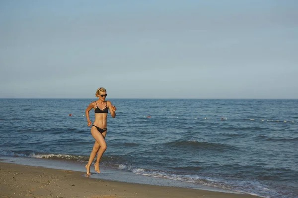 Zijaanzicht van een vrouw die op het strand met de horizon en de zee op de achtergrond worden uitgevoerd — Stockfoto