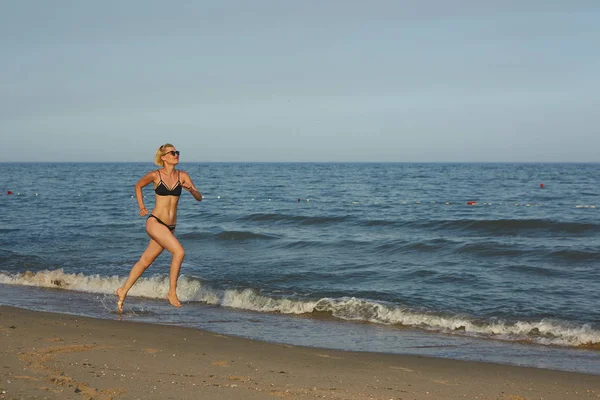 Zijaanzicht van een vrouw die op het strand met de horizon en de zee op de achtergrond worden uitgevoerd — Stockfoto