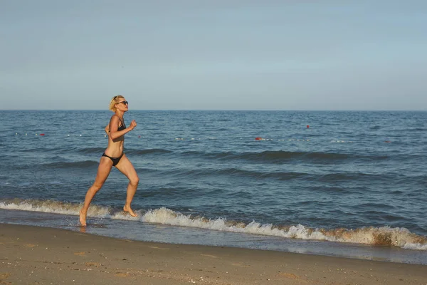 Zijaanzicht van een vrouw die op het strand met de horizon en de zee op de achtergrond worden uitgevoerd — Stockfoto