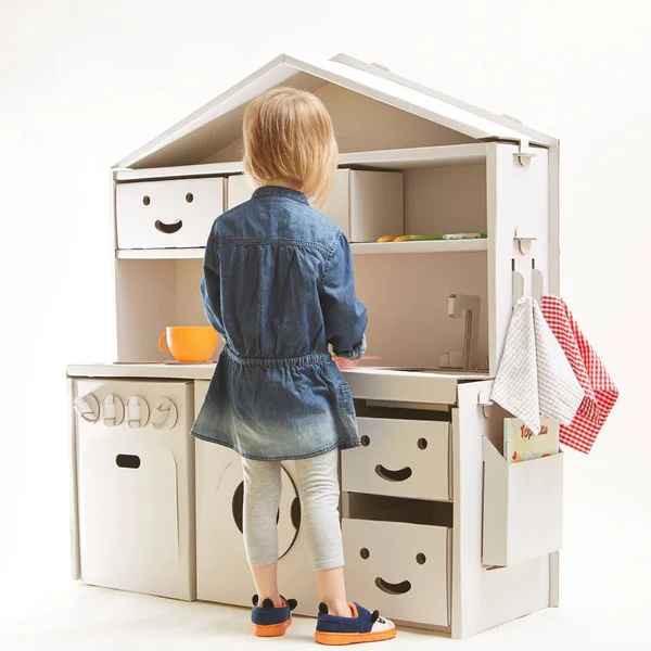Девочка играет с игрушечной кухней дома — стоковое фото
