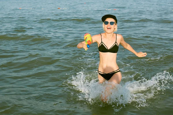 Boldog, fiatal nő, egy sapkát a word királynő játszó vízágyú. Film hatása — Stock Fotó