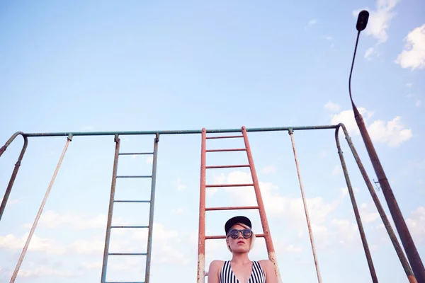 Beautiful woman in black and white striped swimsuit on the old sports ground. Film effect. — Stock Photo, Image