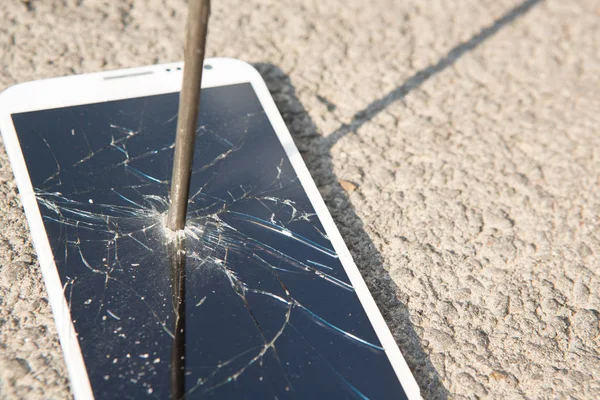 Metal nail and smartphone with a broken screen over the stone surface. The concept of strength. — Stock Photo, Image