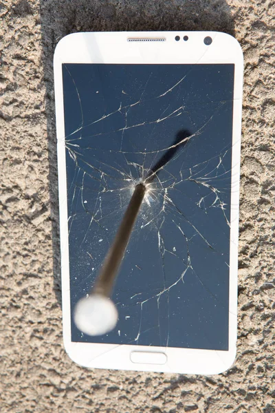 Metal nail and smartphone with a broken screen over the stone surface. The concept of strength. — Stock Photo, Image