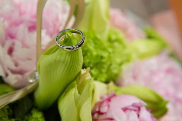 Alliances reposent sur un beau bouquet comme accessoires de mariée — Photo