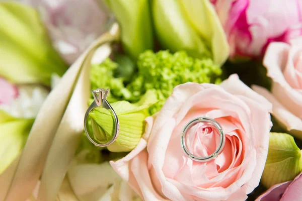 Wedding rings lie on a beautiful bouquet as bridal accessories — Stock Photo, Image