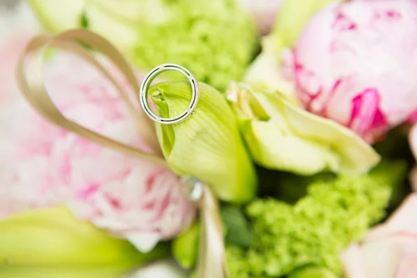 Jegygyűrűk feküdnek egy gyönyörű csokor, mint a menyasszonyi kiegészítők — Stock Fotó