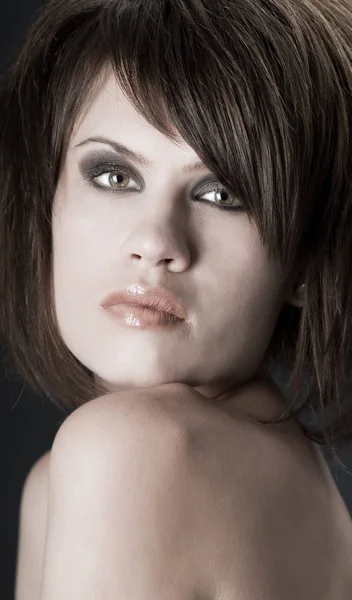 La mujer estricta sexy con maquillaje y un peinado de moda posa en el estudio sobre fondo negro — Foto de Stock
