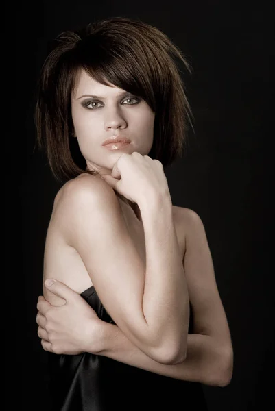 Den sexiga strikta kvinnan med makeup och en fashionabel frisyr poser i studio på svart bakgrund — Stockfoto