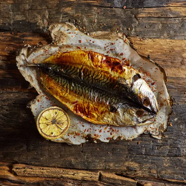 Fish with lime on parchment paper on a black wooden background. Top view. — Stock Photo, Image