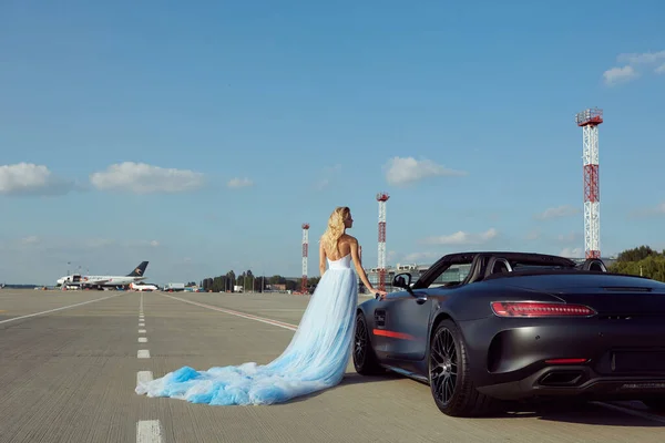 Kyiv, Ukraine - September 2, 2017: The elegant blonde beautiful woman posing near Mercedes Benz AMG GT 50 Edition sports car in airport. A new 2017 supercar designed to celebrate the 50th anniversary — Stock Photo, Image