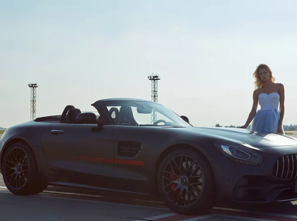 Kiev, Ucrania - 2 de septiembre de 2017: La hermosa mujer rubia elegante posando cerca de Mercedes Benz AMG GT 50 Edition coche deportivo en el aeropuerto. Un nuevo superdeportivo 2017 diseñado para celebrar el 50 aniversario — Foto de Stock