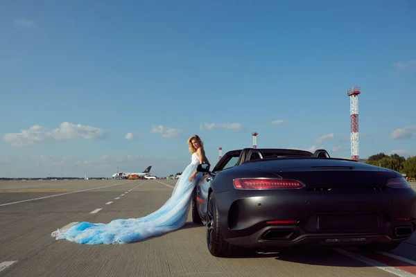 Kiev, Ucrania - 2 de septiembre de 2017: La hermosa mujer rubia elegante posando cerca de Mercedes Benz AMG GT 50 Edition coche deportivo en el aeropuerto. Un nuevo superdeportivo 2017 diseñado para celebrar el 50 aniversario — Foto de Stock